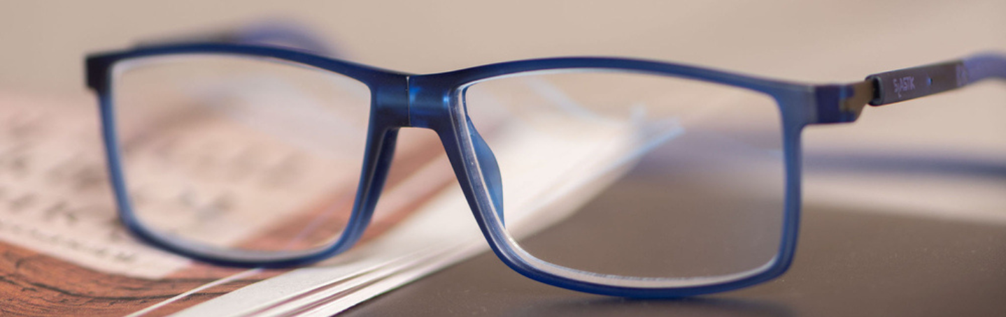 CliC glasses sitting on book, front magnet is closed.