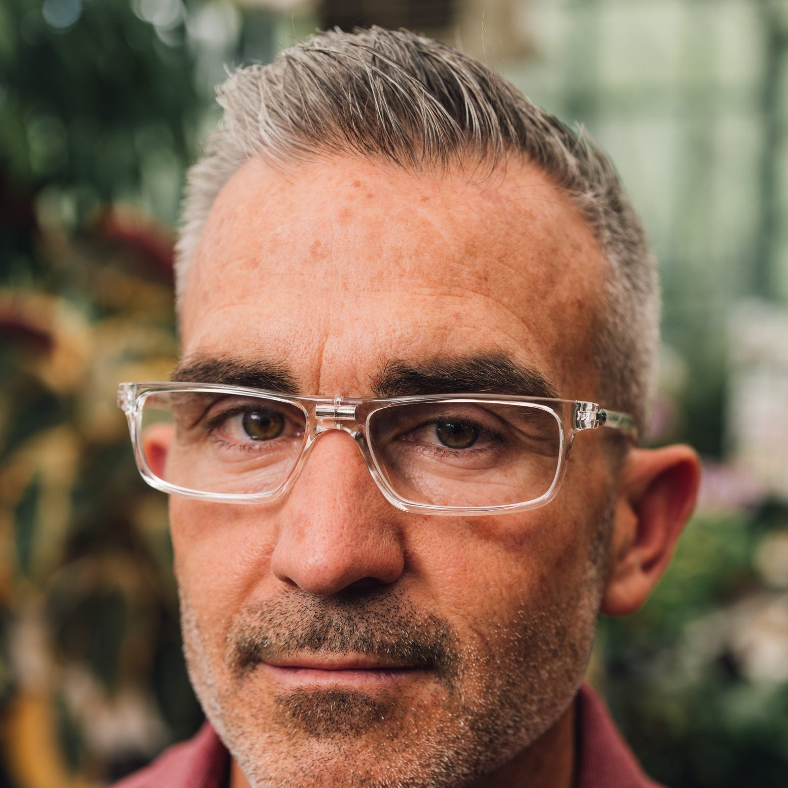 Portrait of a man wearing clear CliC magnetic readers in a greenhouse