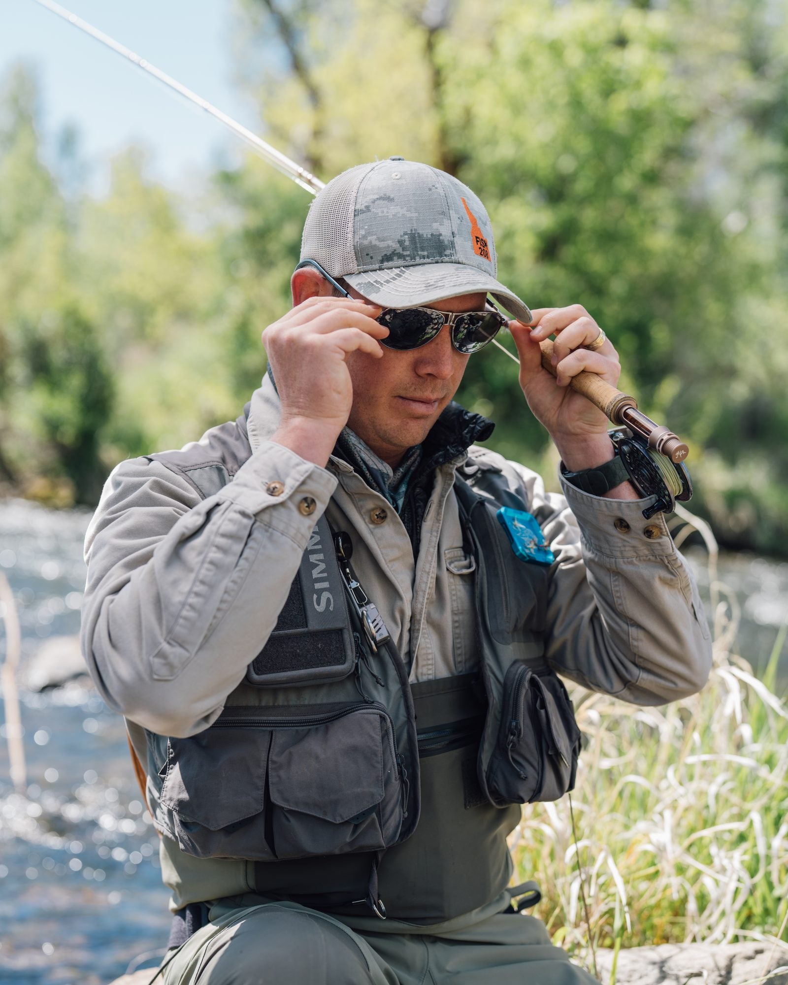 Fly fisherman putting on CliC magnetic sunglasses at the river