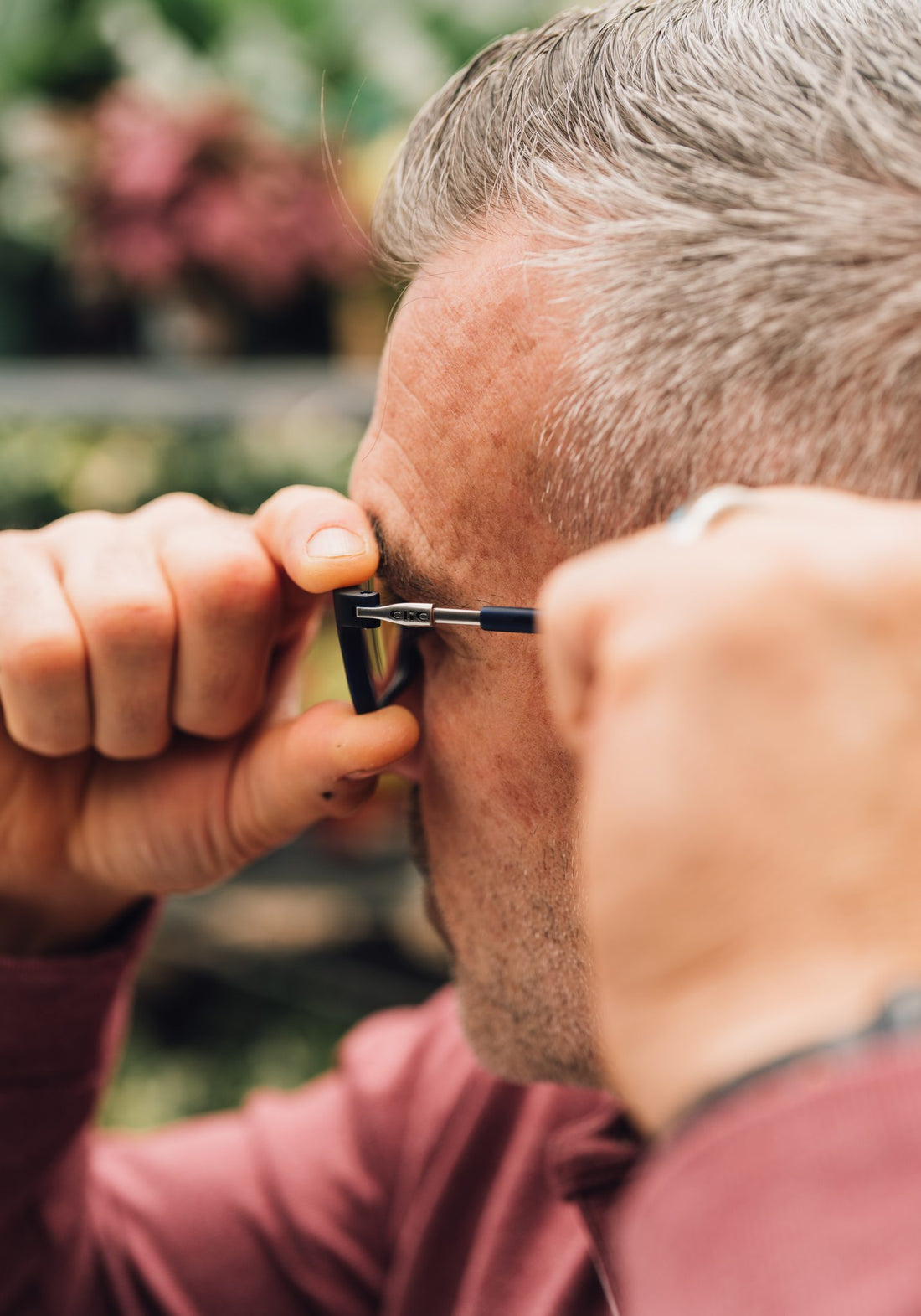 Hands adjusting the temple length of CliC readers behind the ear