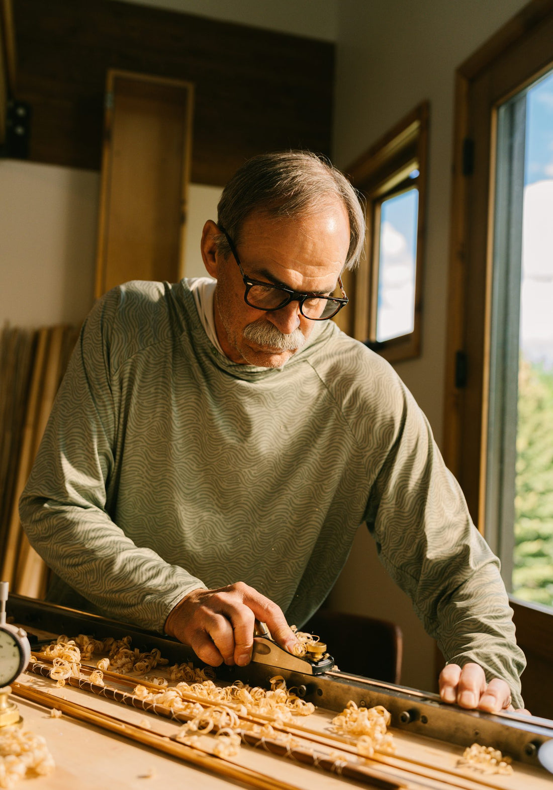 Craftsman planing a bamboo fly rod wearing CliC readers